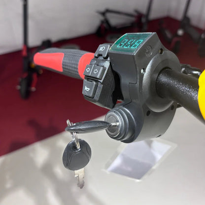 Na sliki je električni skiro model Eco Speed 9. Vidna je ročica s številnimi gumbi za upravljanje, vključno z gumbom za luči in zvok, ter digitalni zaslon, ki prikazuje hitrost. Na ročici je tudi ključ, kar nakazuje, da skiro zahteva ključno upravljanje za zagon. V ozadju so vidni drugi skiroji, kar daje občutek o raznolikosti ponudbe.