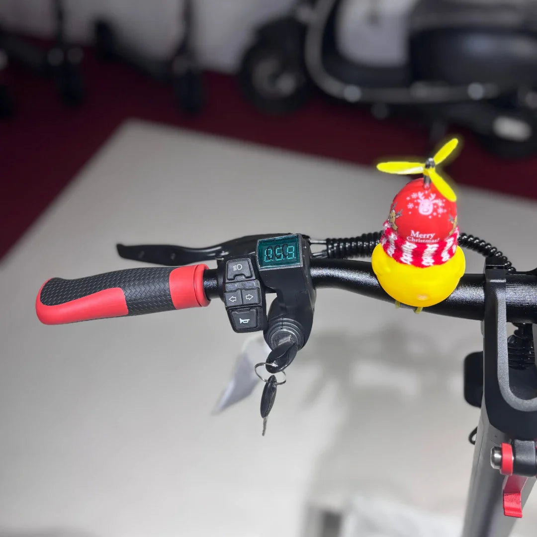 Izdelek na sliki je električni skiro, model Eco Speed 9. Na krmilu so vidni različni gumbi za upravljanje, digitalni zaslon, ki prikazuje hitrost, ter ključi za vklop. Na vrhu krmila je tudi okrasna figura v obliki rumene ptice s prazničnim pokrivalom.