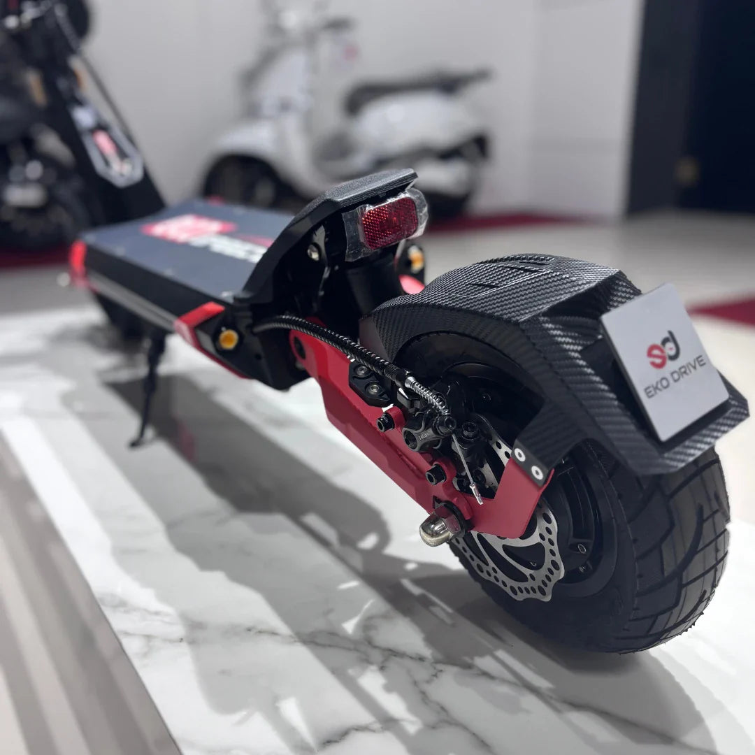 Na sliki je prikazan električni skiro, model "Eco Speed 9". Vidna je zadnja stran skiroja, ki vključuje široko zadnje kolo z disk zavornim sistemom ter svetilko. Ohišje je kombinacija črne in rdeče barve, kar daje športen videz. Na skiroju je tudi oznaka znamke "Eko Drive".