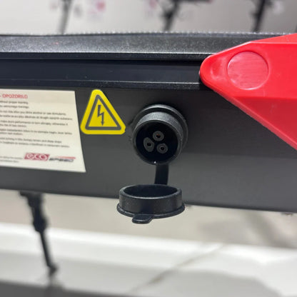 Na sliki je električni skiro model Eco Speed 9. Vidna je polnilna priključna točka, ki je označena s simbolom za električno energijo, kar kaže na električni sistem skiroja. Poleg tega je na sliki tudi zaščitna kapica za priključek, kar nakazuje na skrbno zasnovano funkcionalnost in varnost izdelka.