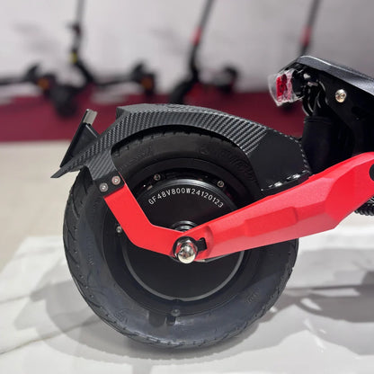 Na sliki je prikazan električni skiro model Eco Speed 9. Vidna je zadnja kolesna enota, ki vključuje motor in gumijasto pnevmatiko. Kolesna enota je opremljena s kovinsko rdečo obrobo in karbonsko zaščito, kar daje skiroju športen videz. V ozadju so vidni še drugi električni skiroji, kar nakazuje, da gre za razstavo ali prodajno mesto.