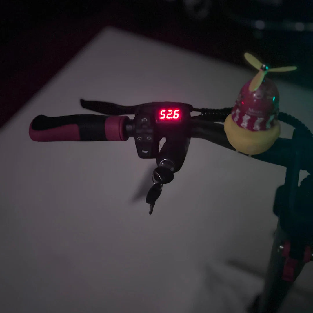 Izdelek na sliki je električni skiro, model Eco Speed 9. Na sliki je prikazano krmilo skiroja s številčnim zaslonom, ki prikazuje hitrost 52.6, ter nekaterimi gumbi in ključi. Na krmilu je tudi majhna igrača v obliki helikopterja.