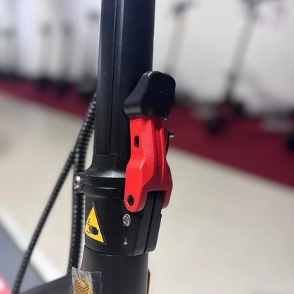 Izdelek je električni skiro, model Eco Speed 9. Na sliki je prikazan del skiroja, ki vključuje mehanizem za zlaganje, označen z rdečo barvo. Vidna je tudi oznaka za varnost in nekaj vijakov, kar nakazuje na robustno konstrukcijo. V ozadju so vidni drugi električni skiroji.