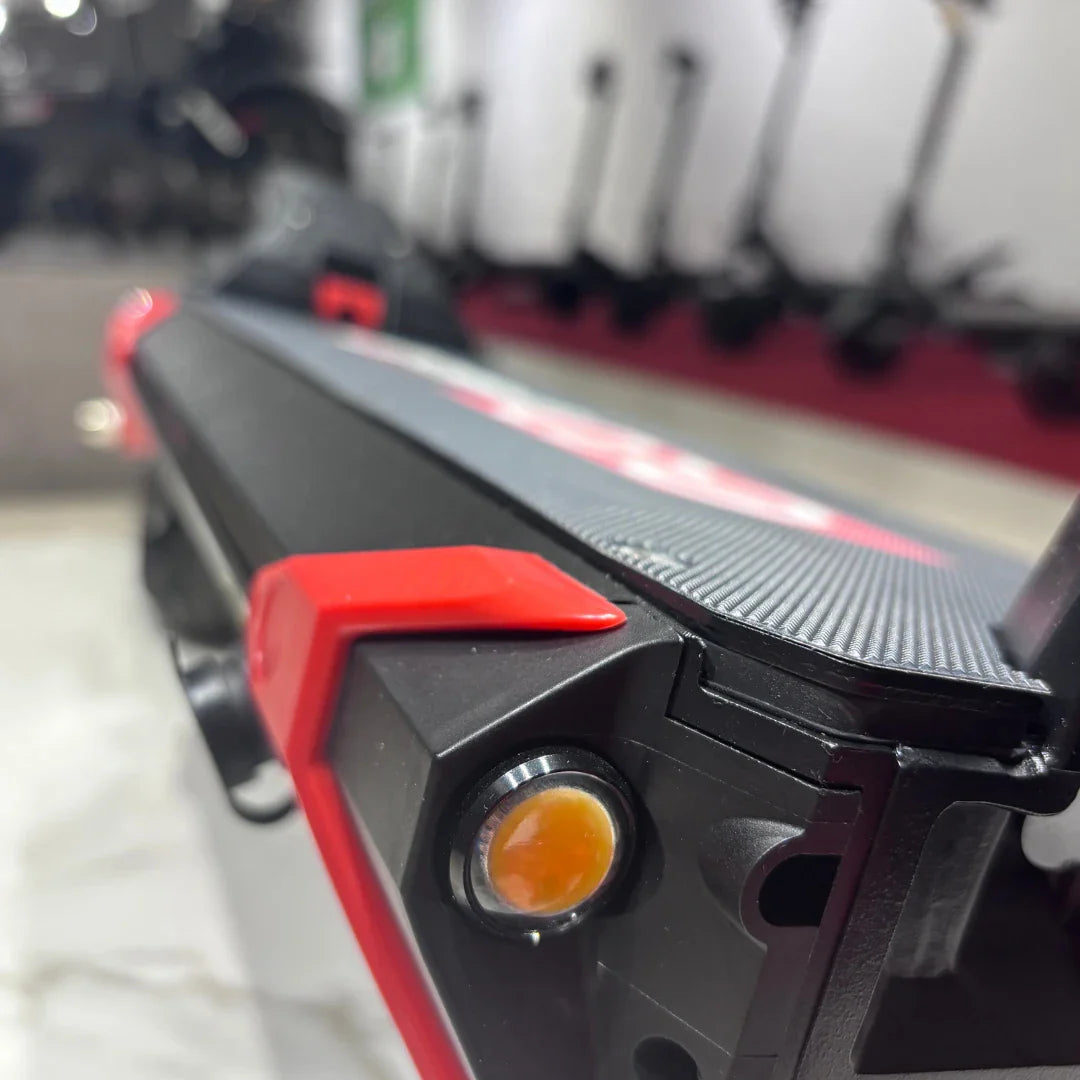 Izdelek je električni skiro, model Eco Speed 9. Na sliki je vidna podrobnost skiroja, kjer se lahko opazi teksturirana površina za boljši oprijem, rdeči detajli ter svetlobni indikator. V ozadju so vidni tudi drugi električni skiroji, kar nakazuje, da je slika posneta v trgovini ali razstavišču.