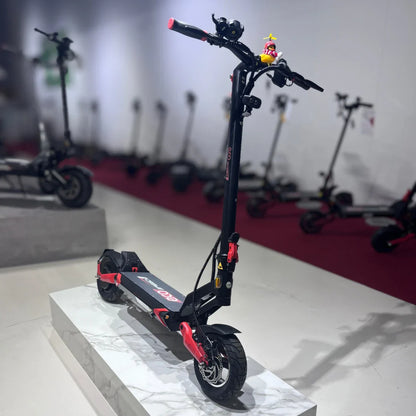 Izdelek na sliki je električni skiro, model Eco Speed 9. Na sliki je skiro v črni barvi z rdečimi detajli, ki stoji na belem podstavku. Vidni so ročaji s kontrolniki, sprednje in zadnje kolo ter disk zavora. V ozadju so še drugi električni skiroji, kar nakazuje, da gre za prodajno mesto ali razstavo.