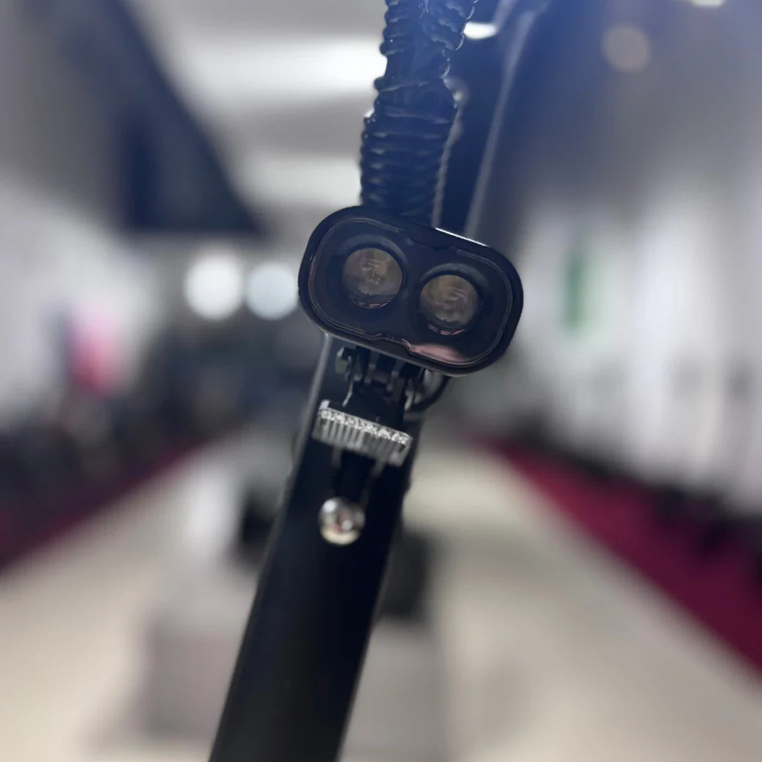 Izdelek na sliki je električni skiro, model Eco Speed 9. Na sliki je vidna sprednja luč skiroja, ki je zasnovana za boljšo vidljivost in varnost med vožnjo. Ozadje je nejasno, vendar se zdi, da je prostor, kjer so razstavljeni različni skiroji.