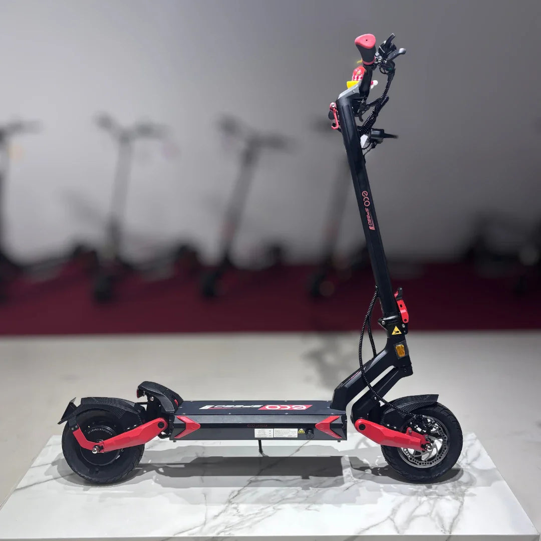 Izdelek na sliki je električni skiro, model Eco Speed 9. Na sliki je prikazan skiro v stranski perspektivi, ki ima črno in rdečo barvno kombinacijo. Vidni so široki kolesi, robustna platforma za stojišče ter krmilo z ročaji. V ozadju so vidni tudi drugi električni skiroji, kar nakazuje, da gre za prodajno okolje.