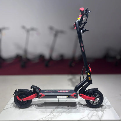 Izdelek na sliki je električni skiro, model Eco Speed 9. Na sliki je prikazan skiro v stranski perspektivi, ki ima črno in rdečo barvno kombinacijo. Vidni so široki kolesi, robustna platforma za stojišče ter krmilo z ročaji. V ozadju so vidni tudi drugi električni skiroji, kar nakazuje, da gre za prodajno okolje.