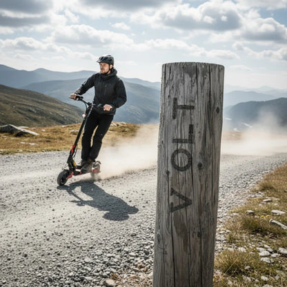 Na sliki je električni skiro, model Eco Speed 9. Zasnova skiroja je športna, uporabnik pa vozi po makadamski poti v naravi. Oblečen je v črno jakno in čelado, kar kaže na varnost pri vožnji. V ozadju so hribi in oblačno nebo, kar ustvarja dinamično in avanturistično vzdušje.