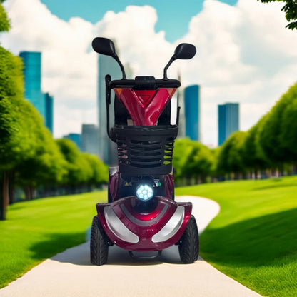 Izdelek je električni mobilni voziček, model Eco Speed Senior. Na sliki je videti voziček v rdeči barvi, ki ima široke pnevmatike in sprednjo luč. Postavljen je na poti ob drevesih, v ozadju pa so vidne moderne zgradbe, kar nakazuje urbano okolje. Voziček je zasnovan za udobno in varno vožnjo, kar je še posebej primerno za starejše uporabnike.