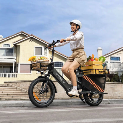 Na sliki je električno kolo znamke Engwe, model LE20. Kolo je opremljeno z dvema košarama, v katerih so vidni različni živilski izdelki, kar nakazuje, da je primerno za prevoz nakupov. Oseba, ki vozi kolo, nosi čelado in se nahaja na cesti pred stanovanjskimi hišami.