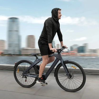 Na sliki je električno kolo znamke Engwe, model Mapfour N1 Pro. Kolo je prikazano v dinamičnem okolju, kjer moški v športni obleki vozi po obali. V ozadju so vidne mestne zgradbe, kar nakazuje urbano okolje. Kolo ima sodoben dizajn z debelimi pnevmatikami in udobnim položajem za vožnjo.