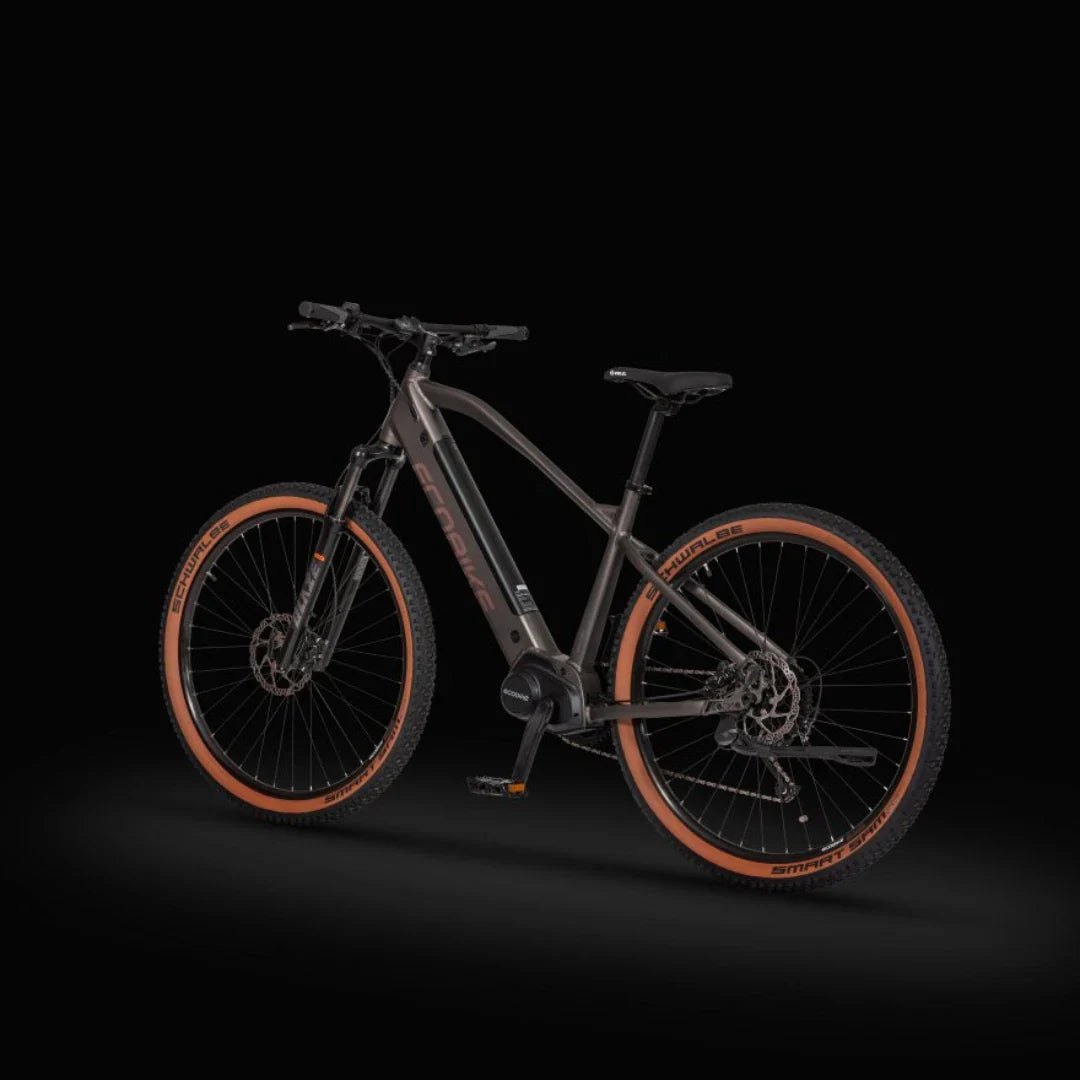 Izdelek na sliki je električno kolo, model Ecobike SX300. Na sliki je kolo v temni barvi, opremljeno s širokimi kolesi in robustnim okvirjem, kar nakazuje na njegovo primernost za vožnjo po zahtevnejših terenih. Vidni so tudi detajli, kot so zavorni sistemi in amortizerji, kar dodatno poudarja njegovo zmogljivost in stabilnost.