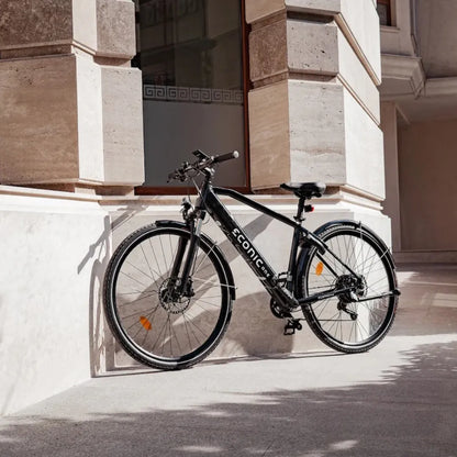 Električno kolo Econic One Smart Urban parkirano ob moderni stavbi, ki prikazuje njegovo elegantno obliko.