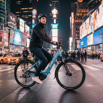 Izdelek na sliki je električno kolo znamke Econo, model Mare City EEC4LK. Na sliki je moški, ki vozi kolo v mestnem okolju, obdan z osvetljenimi reklamami in drugimi ljudmi. Kolo je svetlo modre barve in ima značilnosti mestnega kolesa, kot so udobno sedišče in široke pnevmatike, kar ga naredi primernega za vožnjo po urbanih površinah.