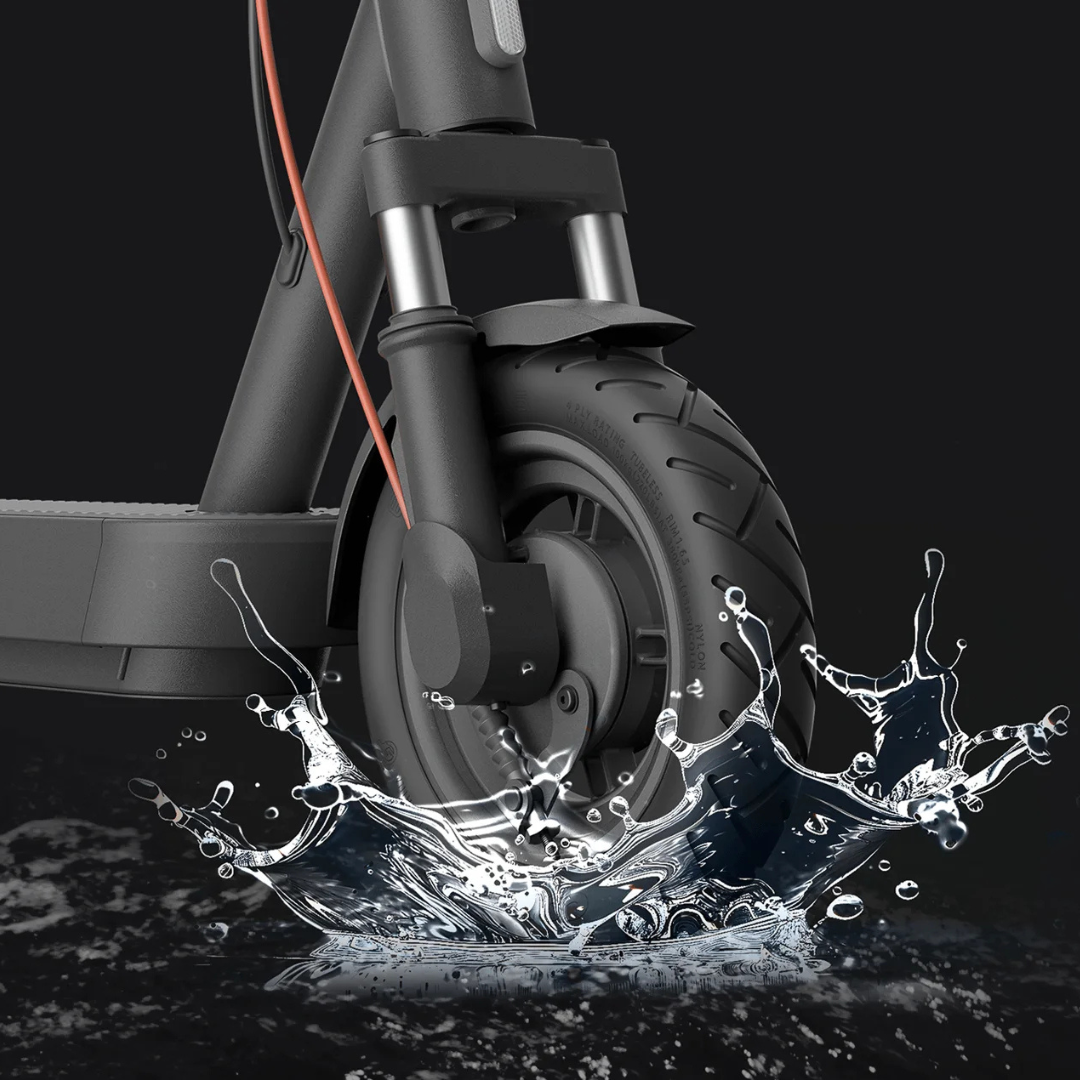 Na sliki je električni skiro znamke Xiaomi, model "Xiaomi 5". Prikazan je sprednji del skiroja, kjer je vidna pnevmatika in vilice. V ozadju je voda, kar nakazuje na vodoodpornost izdelka. Skiro ima sodoben dizajn in robustno konstrukcijo, kar ga naredi primernega za mestno vožnjo.