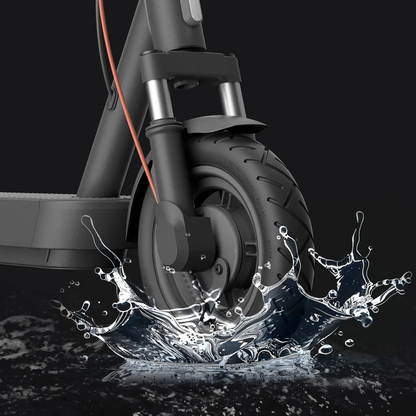 Na sliki je električni skiro znamke Xiaomi, model "Xiaomi 5". Prikazan je sprednji del skiroja, kjer je vidna pnevmatika in vilice. V ozadju je voda, kar nakazuje na vodoodpornost izdelka. Skiro ima sodoben dizajn in robustno konstrukcijo, kar ga naredi primernega za mestno vožnjo.