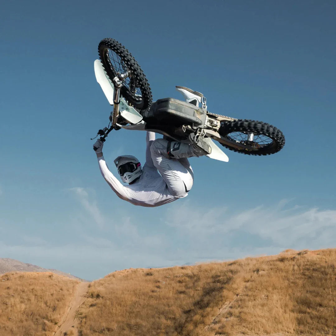 Jezdec izvaja trik na električnem motokros kolesu Stark Varg s čisto nebo v ozadju.