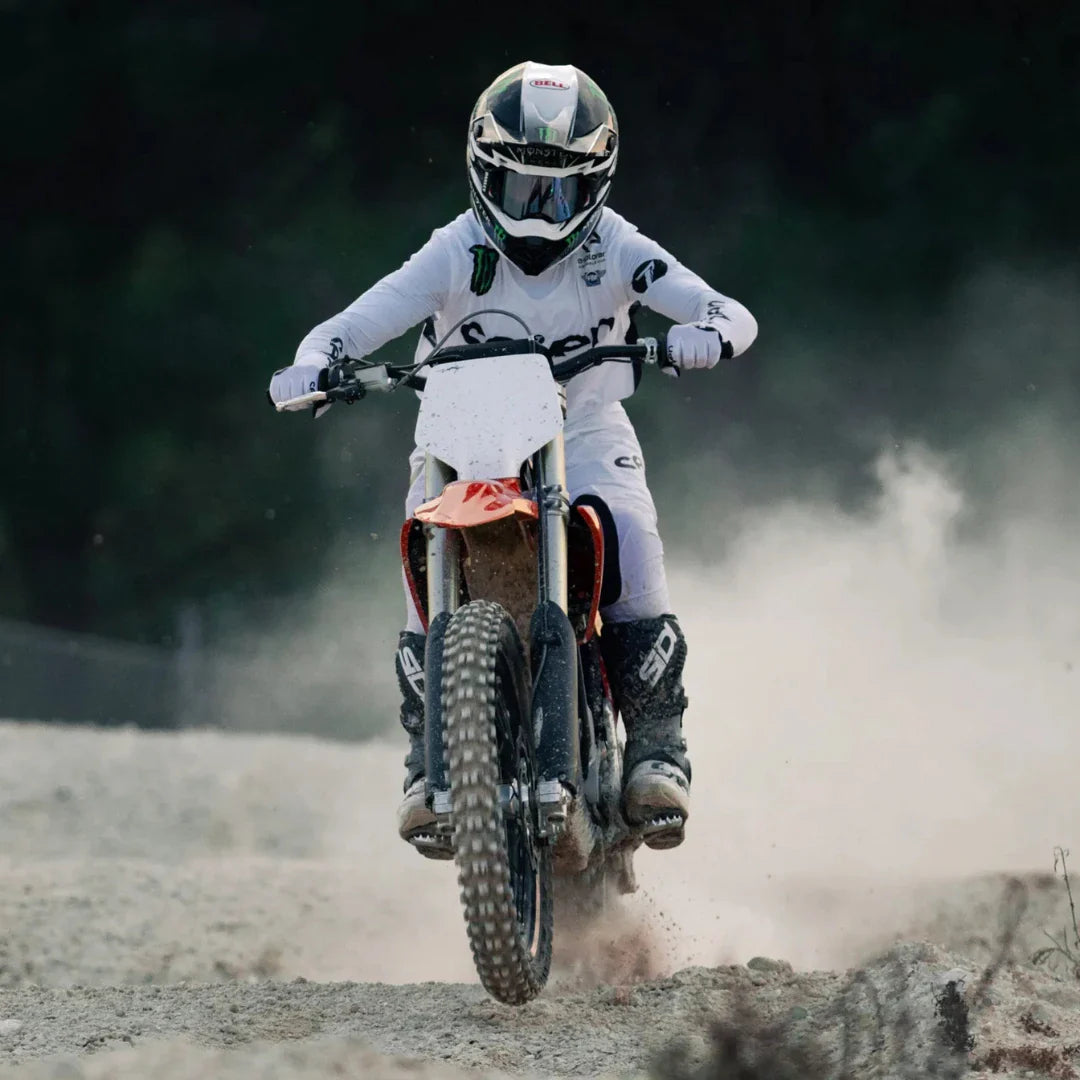 Voznik električnega motokros kolesa Stark Varg dviguje prah na makadamski stezi.