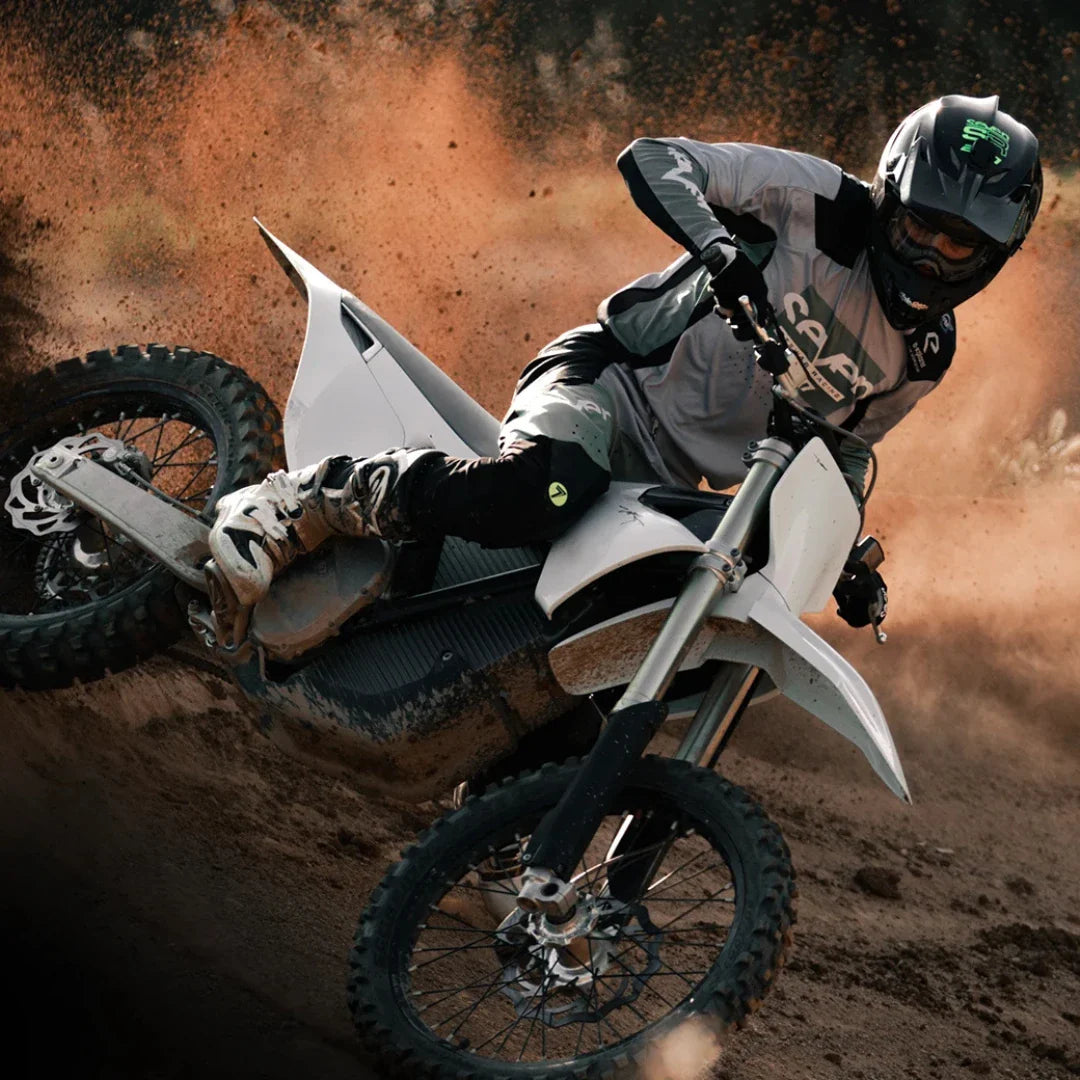 Voznik električnega motokros kolesa Stark Varg dviguje prah med ostro vožnjo skozi ovinek.