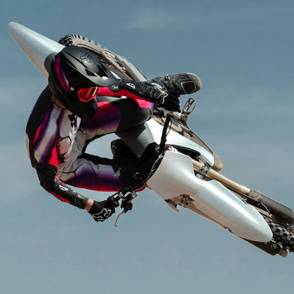 Voznik izvaja trik z električnim motokros kolesom Stark Varg na ozadju jasnega neba.