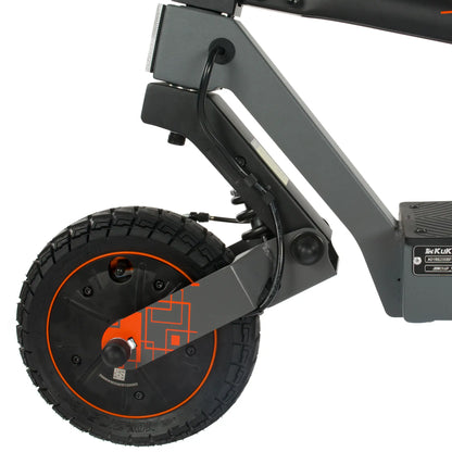 Izdelek na sliki je električni skiro, model Kukirin G2 Ultra. Vidna je zadnja kolesna enota, ki ima robustno pnevmatiko z izrazitim profilom, kar nakazuje na dobro oprijemljivost. Kolo je obrobljeno z oranžnim detajlom, kar daje skiroju dinamičen videz. Na okvirju je tudi del, ki omogoča prilagodljivo vzmetenje, kar prispeva k udobnejši vožnji.