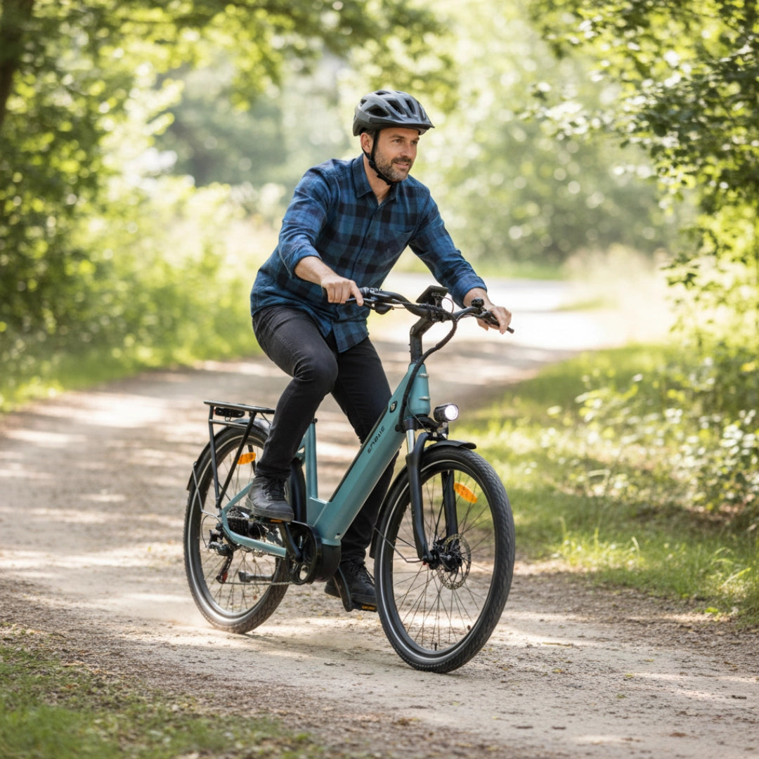 Na sliki je električno kolo znamke Engwe, model P275 SE. Vidimo moškega, ki vozi kolo po gozdni poti, oblečenega v karirasto srajco in čelado. Kolo ima moderno zasnovo in je opremljeno z lučjo ter nosilcem za prtljago. Okolica je zelena in naravna, kar ustvarja prijetno vzdušje za vožnjo.