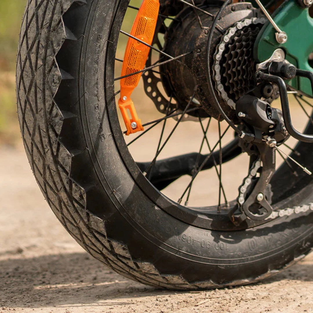 Izdelek je električno kolo, znamke Engwe, model EP-2 3.0 Boost. Na sliki je prikazan zadnji kolesni del kolesa, ki vključuje široko pnevmatiko z izrazitim profilom, verigo in zadnji menjalnik, kar nakazuje na robustno zasnovo, primerno za različne terene. Vidna je tudi reflektorja za večjo varnost med vožnjo.