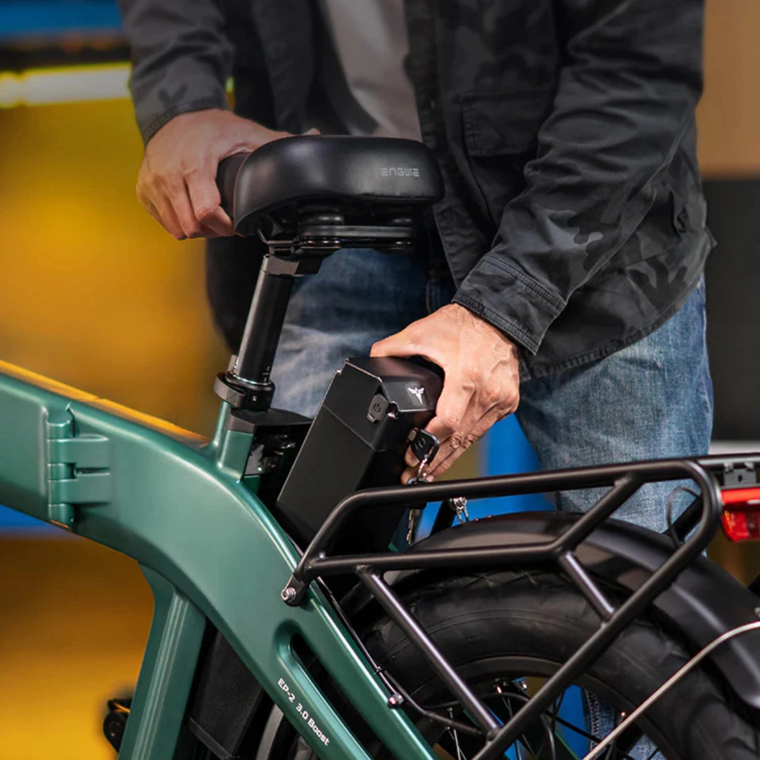 Na sliki je električno kolo znamke Engwe, model EP-2 3.0 Boost. Vidimo osebo, ki odstranjuje baterijo iz okvirja kolesa, kar nakazuje na enostavno zamenjavo ali polnjenje baterije. Kolo ima robustno zasnovo s širokimi pnevmatikami in nosilcem za prtljago.