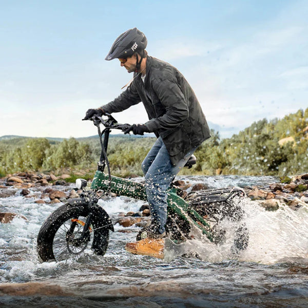 Na sliki je električno kolo znamke Engwe, model EP-2 3.0 Boost. Kolo je prikazano med vožnjo po rečnem toku, kar kaže na njegovo sposobnost premagovanja zahtevnih terenov. Kolesar nosi zaščitno čelado in oblačila, primerna za vožnjo, medtem ko se okoli njega razpršijo kapljice vode.