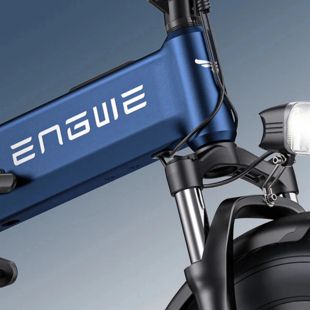 Izdelek je električno kolo, znamke Engwe, model Engine Pro 3.0 Boost. Na sliki je prikazan del okvirja kolesa v modri barvi, ki vsebuje logotip znamke, ter sprednji del s svetilko in vilicami, kar nakazuje na robustno zasnovo in funkcionalnost kolesa.