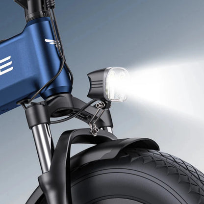 Izdelek na sliki je električno kolo, model Engwe Engine Pro 3.0 Boost. Na sliki je vidna sprednja luč, ki je pritrjena na okvir kolesa, ter del sprednjega kolesa z robustnim gumijastim profilom, kar nakazuje na njegovo zmogljivost in stabilnost. Kolo ima modro barvo okvirja in sodoben dizajn.