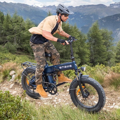 Na sliki je električno kolo, model Engwe Engine Pro 3.0 Boost. Kolo je vidno v naravnem okolju, kjer moški vozi kolo po neurejeni poti. Ima široke gume in je opremljeno z nosilcem za prtljago. Moški nosi čelado in športna oblačila, kar nakazuje na aktivno uporabo kolesa v naravi.