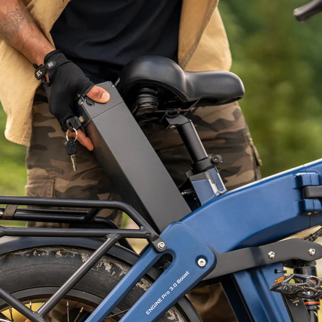 Na sliki je električno kolo znamke Engwe, model Engine Pro 3.0 Boost. Prikazan je del kolesa, kjer uporabnik odstranjuje baterijo, ki je nameščena na zadnjem delu okvirja. Kolo ima robustno zasnovo s širokimi pnevmatikami, kar nakazuje na njegovo primernost za različne terene.