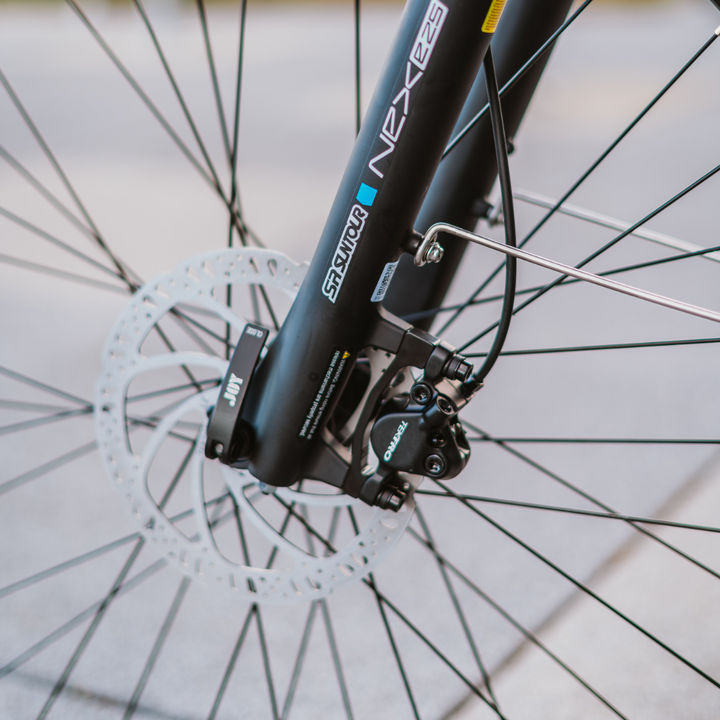 Na sliki je prikaz delov električnega kolesa, modela Econo Apes EER4. Vidni so sprednji del okvirja, zavorni sistem in disk zavore. Zavorni mehanizem je nameščen na sprednjem kolesu, kar kaže na kakovostno opremo, ki omogoča učinkovito zaviranje. Kolo ima sodoben dizajn in je primerno za mestno vožnjo ter rekreacijo.