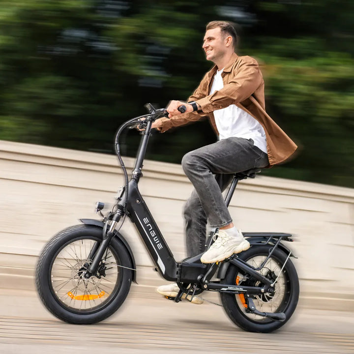 Moški se vozi z električnim kolesom Engwe L20 3.0 Boost na sončen dan in se smeji med poganjanjem pedal.