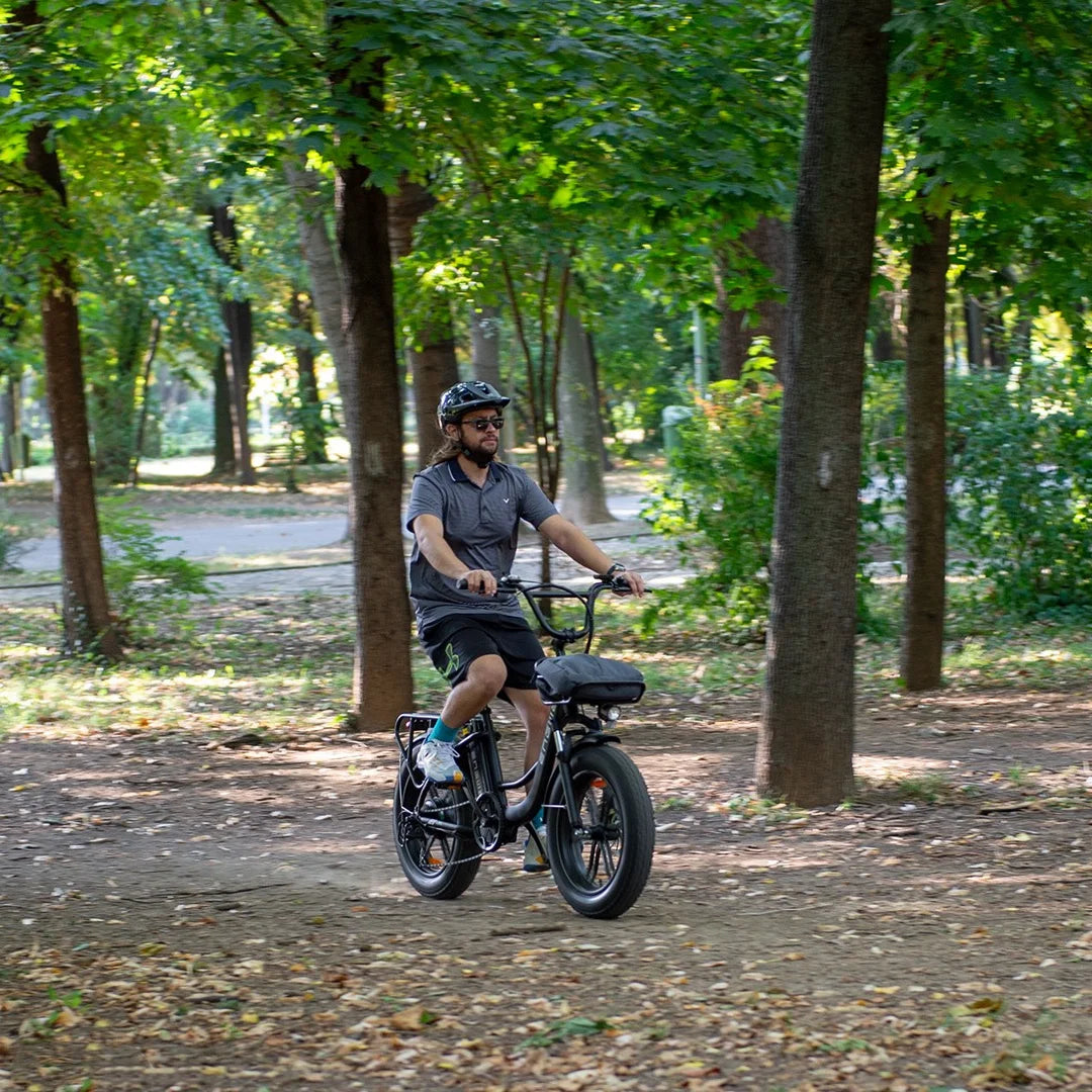 Moški se vozi z električnim kolesom Engwe L20 po gozdni parkovni poti.