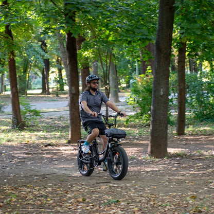 Moški se vozi z električnim kolesom Engwe L20 po gozdni parkovni poti.