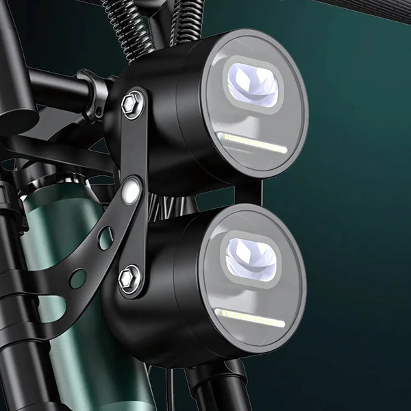 Na sliki je prikaz električnega kolesa, model Engwe M20. Vidni so sprednji svetili, ki sta nameščeni na okvirju kolesa. Svetili sta okrogli in imata sodoben dizajn, kar nakazuje na funkcionalnost in estetsko privlačnost izdelka. Oba svetila sta pritrjena z nosilcem, kar zagotavlja stabilnost in varnost med vožnjo.