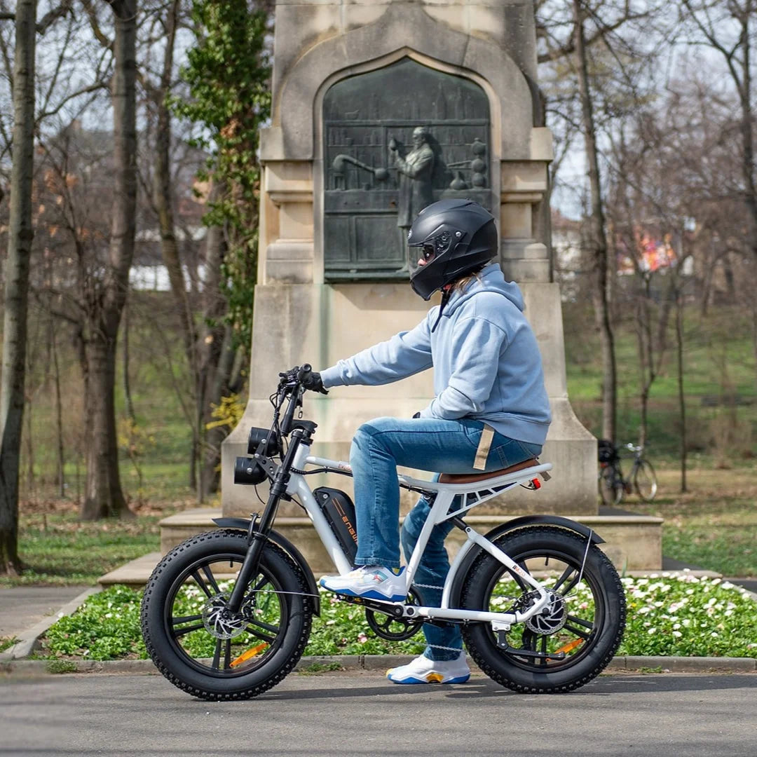 Oseba vozi električno kolo Engwe M20 v parku, nosi čelado in priložnostna oblačila.