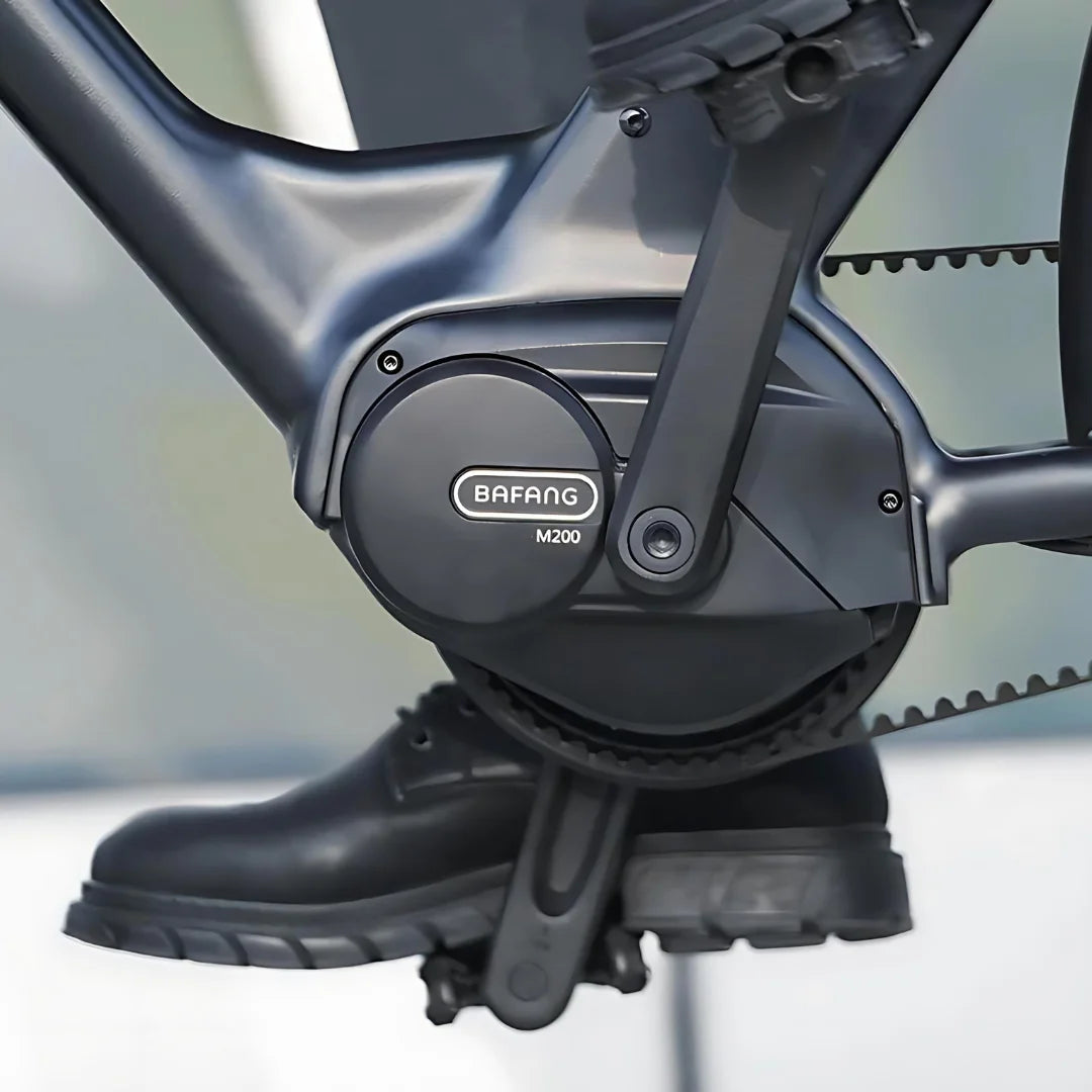 Na sliki je električno kolo znamke Engwe, model P275 Pro. Vidna je pogonska enota Bafang M200, ki je nameščena na okvirju kolesa. Prikazan je tudi del pedalov in čevlji, kar nakazuje, da je kolo zasnovano za udobno vožnjo.