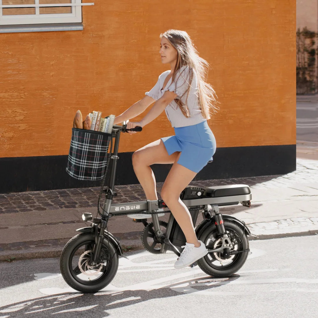 Ženska se vozi z električnim kolesom Engwe T14 s košaro živil v urbanem okolju.