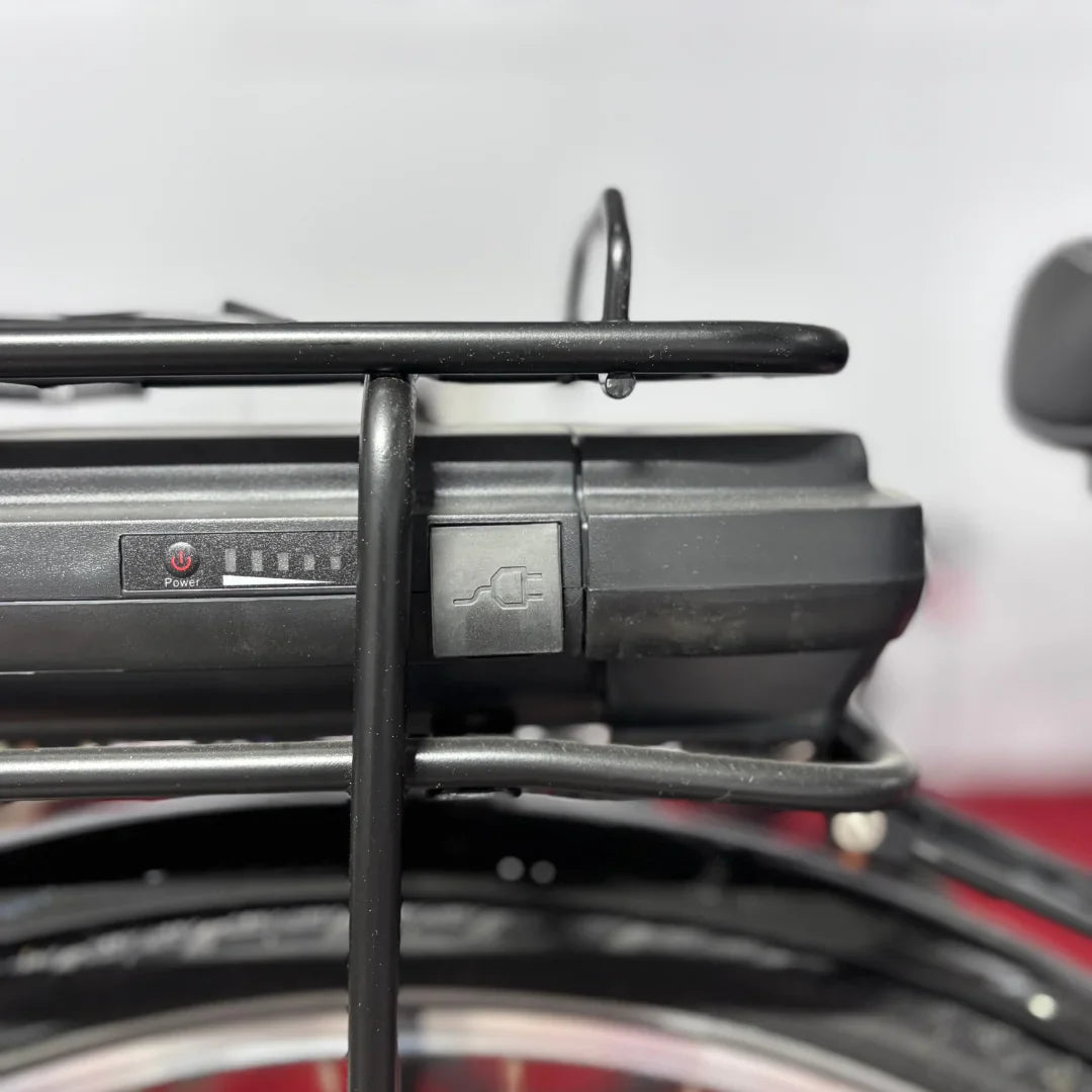 Na sliki je električno kolo znamke Fischer, model Cita 1.0. Vidna je baterija, nameščena na zadnjem nosilcu, z gumbom za vklop in indikatorjem napolnjenosti. Baterija ima tudi priključek za polnjenje, kar nakazuje na električni sistem kolesa.