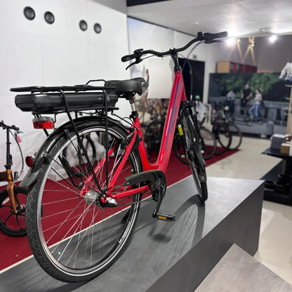 Izdelek na sliki je električno kolo znamke Fischer, model Cita 1.0. Kolo je v svetlo rdeči barvi in ima nameščen akumulator na zadnjem delu okvirja. Vidna je tudi klasična zasnova z dvema kolesoma, krmilom in pedalom, kar je značilno za električna kolesa. V ozadju so vidni drugi kolesi in prostoren prostor za razstavo.