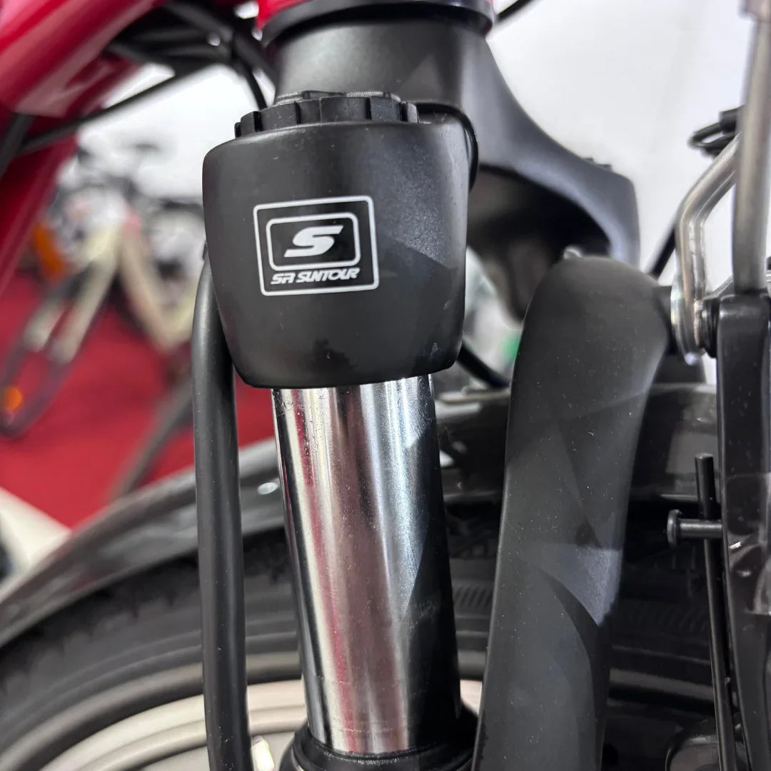 Izdelek na sliki je električno kolo, model Fischer Cita 1.0. Na sliki je prikazan del sprednje vilice, kjer je vidna oznaka znamke SR Suntour, kar nakazuje na kakovostno vzmetenje. Kolo je verjetno zasnovano za udobno vožnjo in enostavno upravljanje.