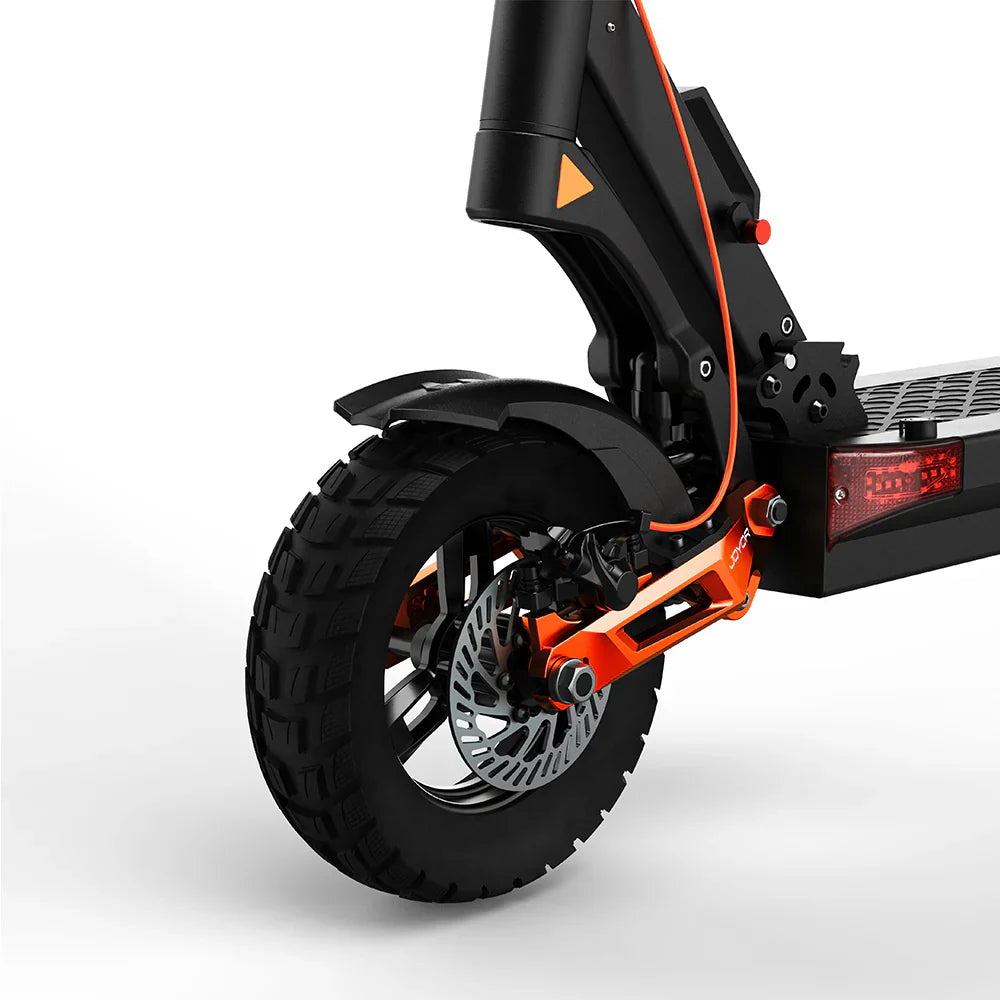 The product is the Joyor T6 electric scooter. The image shows the scooter's front wheel assembly, which includes a robust tire with a deep tread for better grip. The brake and part of the frame, designed for stability and durability, are also visible. The black and orange color combination adds a dynamic look.