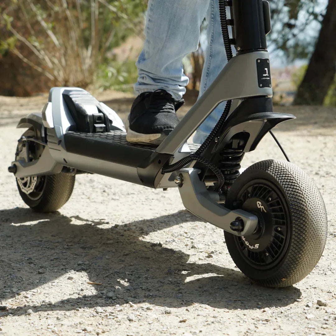 Posnetek od blizu stopala na električnem skiroju Joyor Luxerider na makadamski poti.