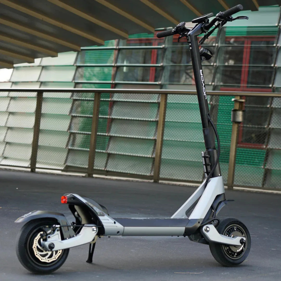 Eleganten električni skiro Joyor Luxerider parkiran na sodobni urbani površini.