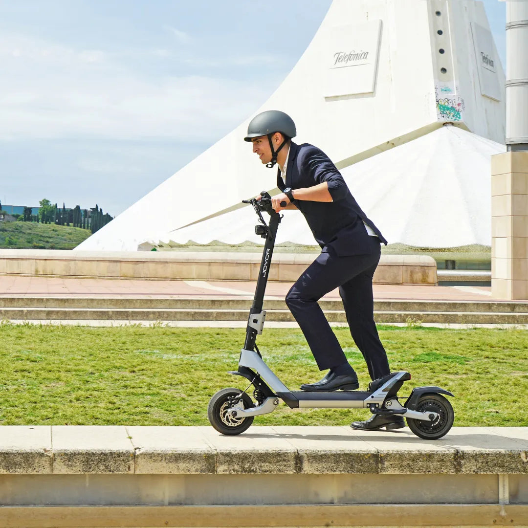 Moški v obleki se vozi z električnim skirojem Joyor Luxerider po poti.