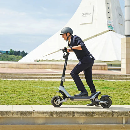 Moški v obleki se vozi z električnim skirojem Joyor Luxerider po poti.